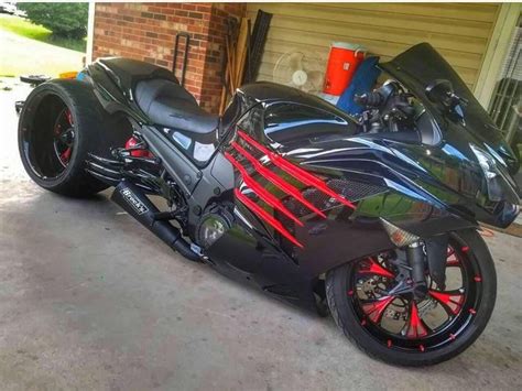 Black Motorcycle With Red And Blue Stripes Parked In Front Of A Garage