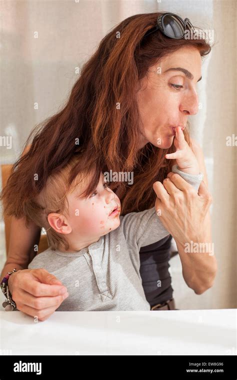 Brunette Woman Mother With Sunglasses On Head Sucking Finger Of Her Blonde Baby Two Years Age