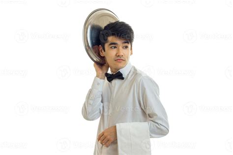 funny handsome waiter looks away and keeps the dish tray near his head ...