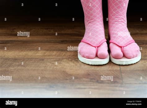Female Feet In Socks With Pink Flip Flops On Floor Background Stock