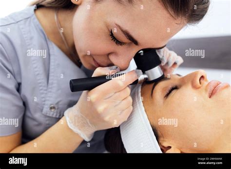 Doctor dermatologist examines skin of client face of beauty salon with ...