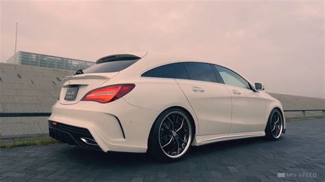 The Rear End Of A White Mercedes Cla Parked In Front Of A Concrete Wall