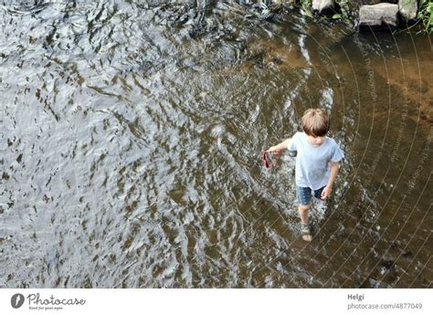 Junge schlendert lässig mit Sonnenbrille in der Hand am Ufer der Fulda