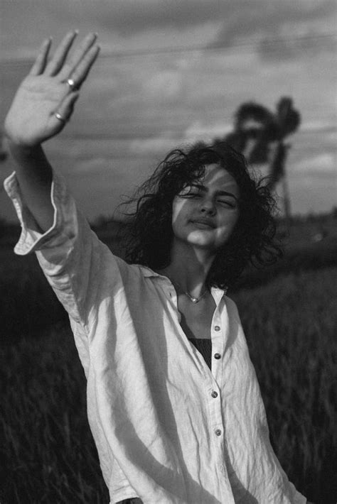 A Woman Standing In A Field Holding Her Hands Up