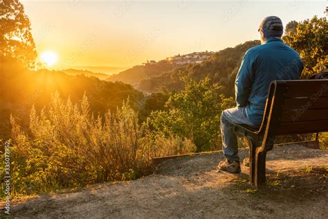 Foto De Person Man Sitting On A Bench Watching The Sunrise Over Hills