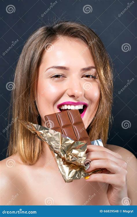 Belle Jeune Femme Blonde Nue Avec Le Maquillage Lumineux Mangeant La Barre De Chocolat Photo