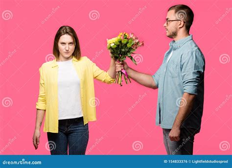 Young Man Presenting Bouquet Of Flowers To Angry Woman Isolated Stock