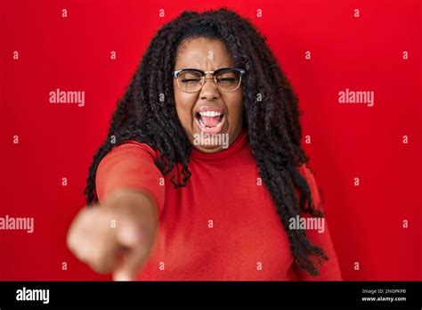 Plus Size Hispanic Woman Standing Over Red Background Pointing Displeased And Frustrated To The