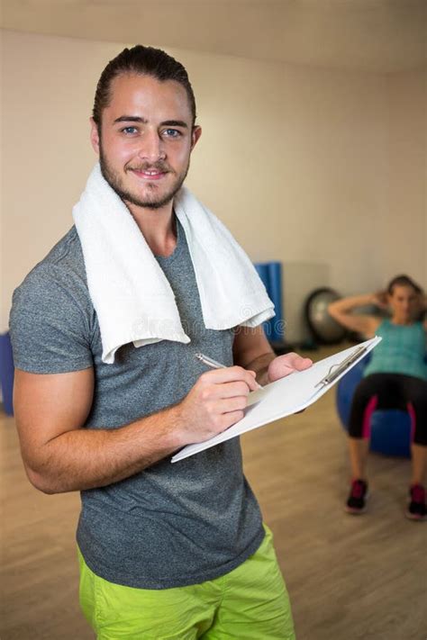 Portrait Of Smiling Fitness Trainer Writing On Clipboard Stock Image