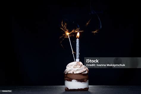 Delicious Birthday Cupcake With Firework Candle On Table Against Dark