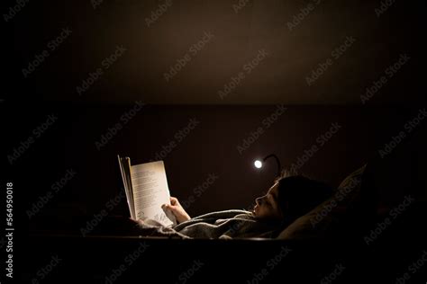 Young girl reading before bedtime in bed with lamp Stock Photo | Adobe ...