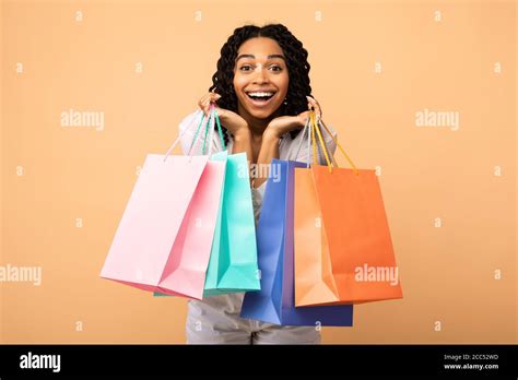 African American Girl Posing With Shopper Bags Over Beige Background