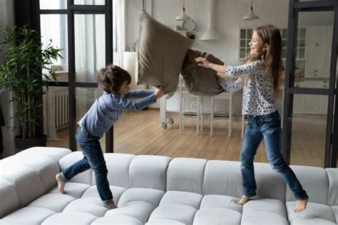 Petite Soeur Et Frère Ravi Pillow Combat Sauter Sur Le Canapé Image