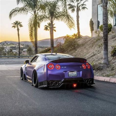 A Purple Sports Car Parked On The Side Of A Road With Palm Trees In The Background