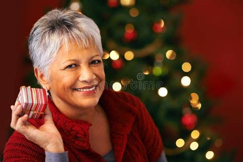I Wonder Whats Inside A Mature Woman Holding A Christmas Present To Her Ear Stock Image