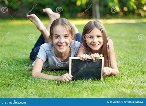 Portrait De Deux Filles Se Trouvant Sur Lherbe Avec Le Tableau Photo