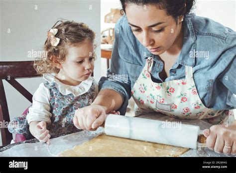 Mother And Daughter Baking Cookies In The Kitchen Flattening Pastry