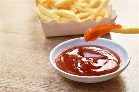 French Fries Mixed With Salt In Paper Box Dipping Ketchup On Table