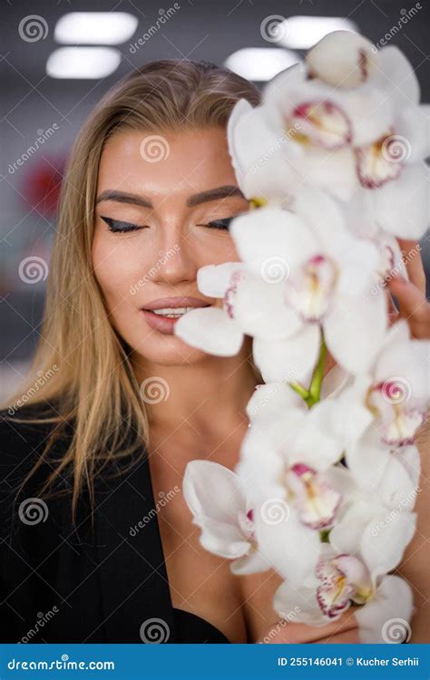 Portrait Of Seductive Blonde Woman With Orchid Branch In Her Hands