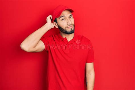 Hispanic Man With Beard Wearing Delivery Uniform And Cap Confuse And