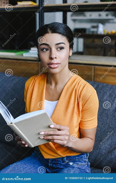 Beautiful Mixed Race Girl In Orange Shirt Holding Book In Living Room