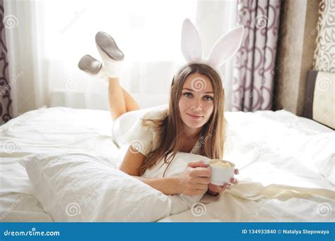 Lovely Brunette Girl With Bunny Ears On Her Head And Lying With Coffee