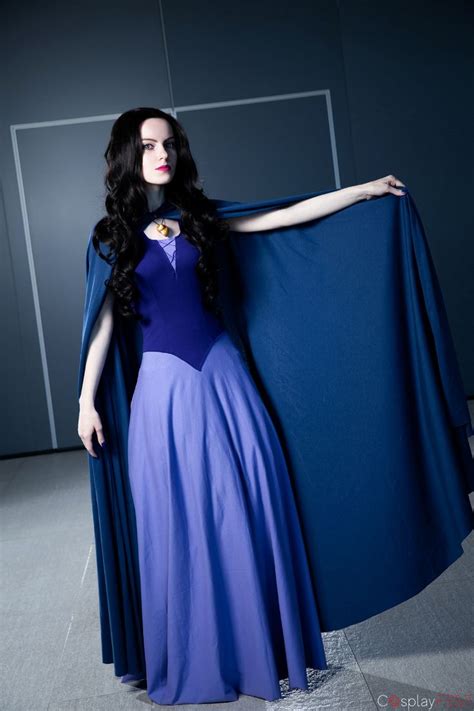 A Woman In A Blue And Purple Dress Is Holding A Cape