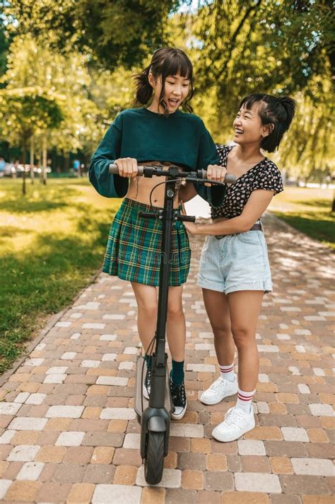 Chicas Lindas Y Delgadas Montando Una Moto En El Parque Imagen De