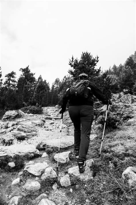 A person walking up a rocky hill with ski poles photo – Free Adventure