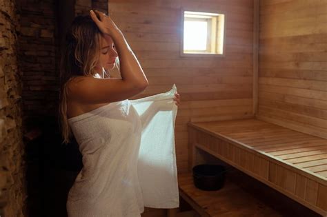 Uma Jovem Relaxa E Transpira Em Uma Sauna Quente Embrulhada Em Uma