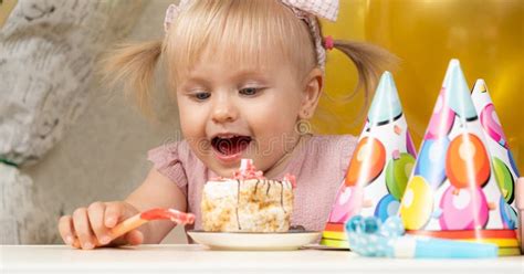 Two Year Old Blonde Girl Eating Birthday Cake On Her Birthday Stock