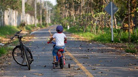 Un Chico Lindo Andando En Bicicleta Cerca De La Bicicleta Grande De Su