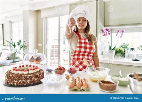 Beautiful Young Brunette Pastry Chef Woman Cooking Pastries At The Kitchen Looking Unhappy And