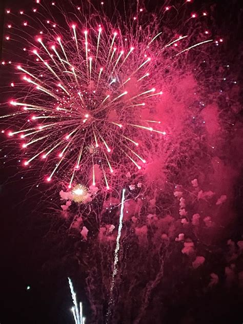 Fireworks Are Lit Up In The Night Sky With Pink And Red Lights On It S Side