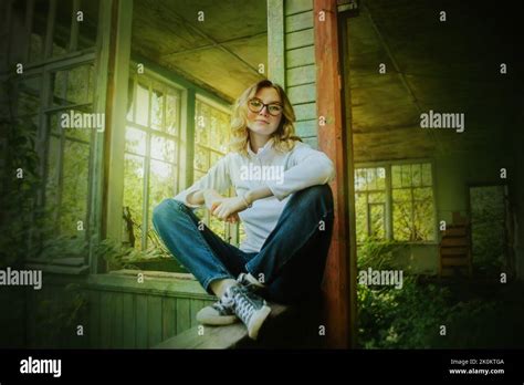 Une Jolie Fille Blonde En Jeans Et Baskets Bleus Est Assise Sur La Main Courante En Bois D Une