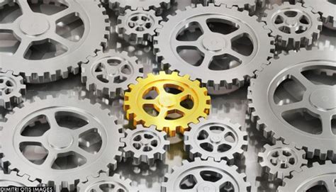 System Of Silver Gear Cogs With One Golden Cog In The Centre