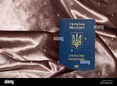 A Foreign Ukrainian Passport Stands On A Pink Crumpled Fabric A