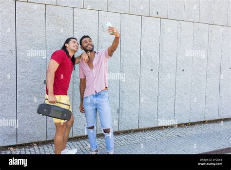 A Joyful Multiethnic Gay Couple Capturing A Selfie In A City Environment Showcasing Their