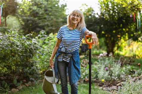 Mature Woman Watering Plants In Her Garden Stock Image Image Of Older