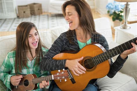 Caucasian Mother And Daughter Singing With Guitar And Ukulele Stock