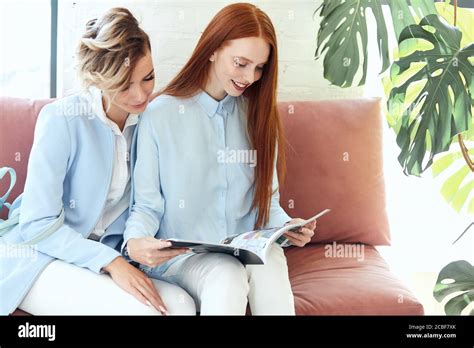 Redhead And Blonde Women Sit On Sofa And Enjoy Looking Journal Modern