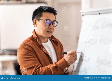 Korean Male Teacher Having Class Writing On Whiteboard In Classroom