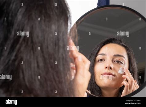 Over Shoulder View Of Caucasian Girl Applying Moisturizer Cream To Her