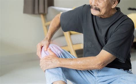 Close Up Of Senior Man Sitting On Floor And Suffering From Knee Ache