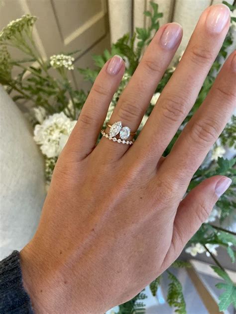 A Woman S Hand With A Ring On It And Flowers In The Back Ground