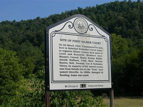 a sign is in front of some trees and bushes on the side of a hill