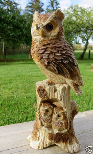 An Owl Statue Sitting On Top Of A Tree Stump