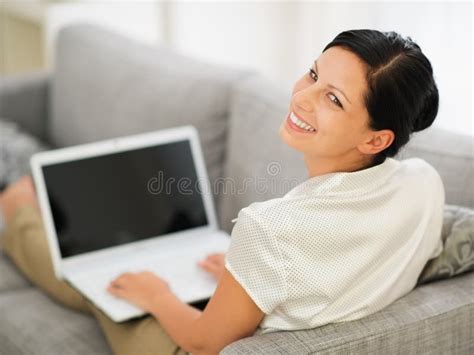 Attractive Young Woman Sitting On Couch With Laptop Computer Stock