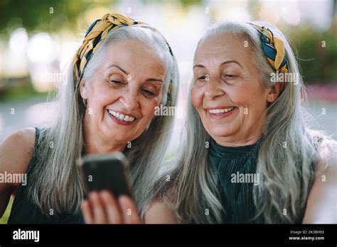 Senior Women Twins Outdoors In City Checking Smartphone Stock Photo Alamy