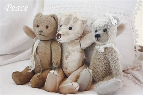 Three Stuffed Teddy Bears Sitting Next To Each Other On A White Bed